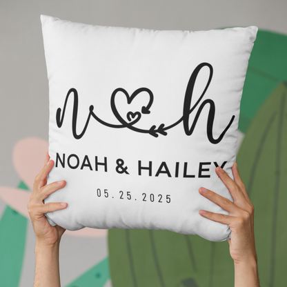 White pillow with personalized name and date design held by hands against a blurred background