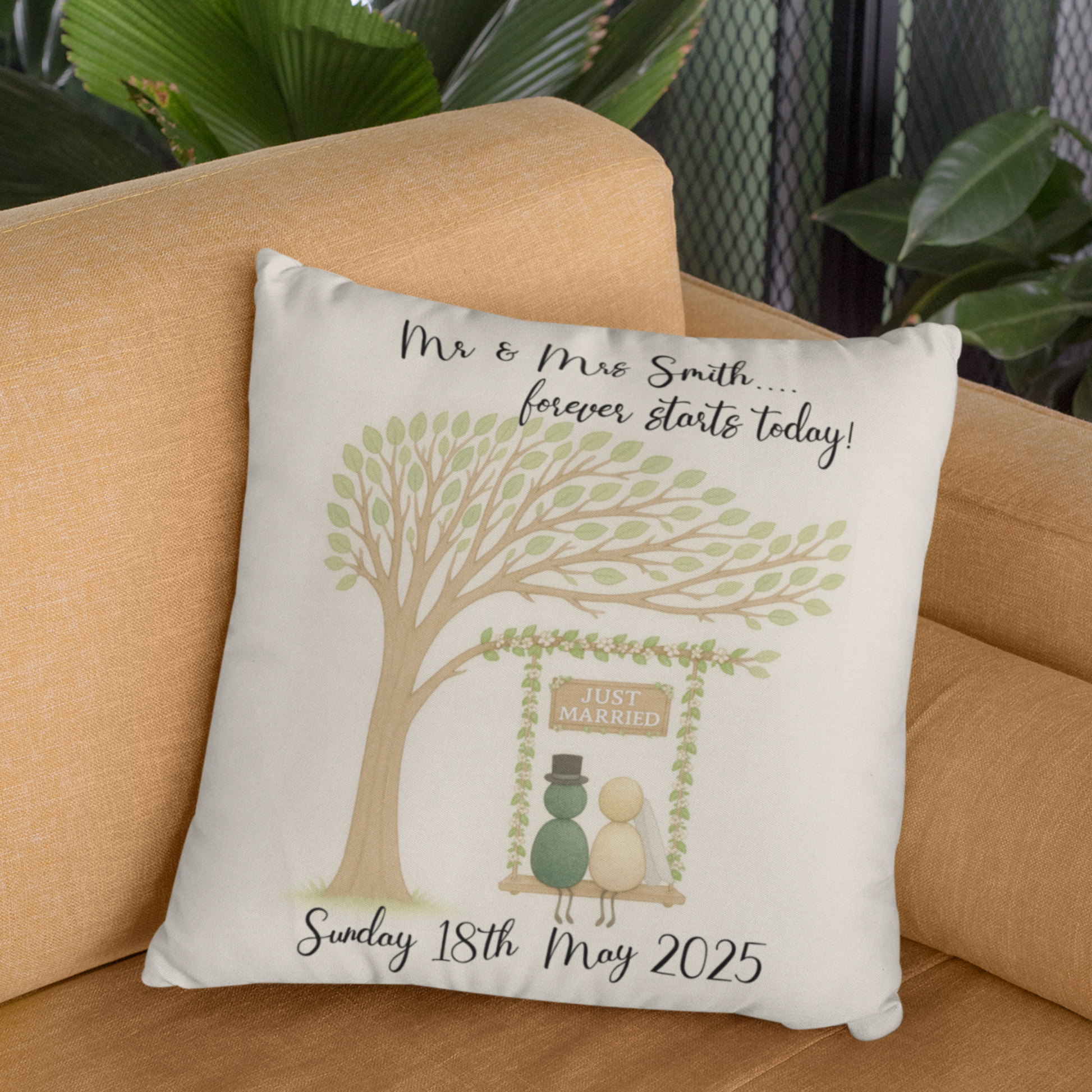 Decorative pillow with a tree and house illustration on a beige couch.