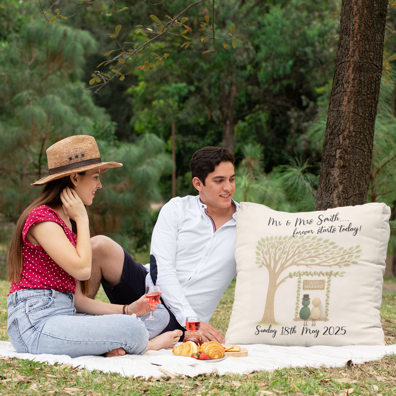 Couple sitting on a blanket with a personalized pillow in a park