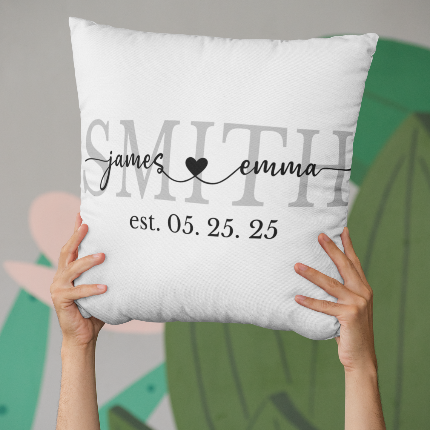 White pillow with personalized text held by hands against a blurred background
