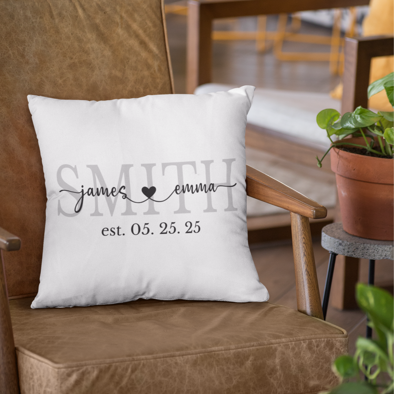 White pillow with personalized text on a brown chair in a cozy indoor setting.